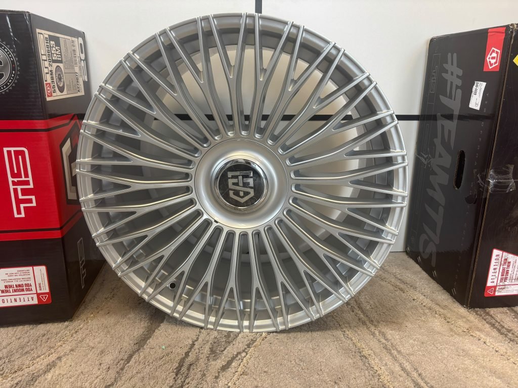 Modern multi-spoke aluminum alloy wheel mounted on a car, three-quarter studio view